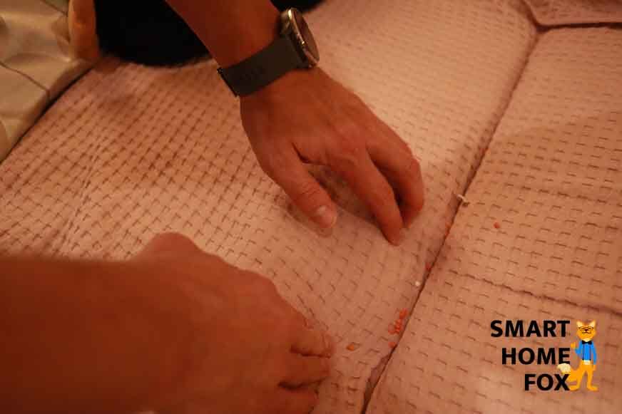 Man sieht Dreck im Zwischenraum zwischen Polstern eines Sofas. 